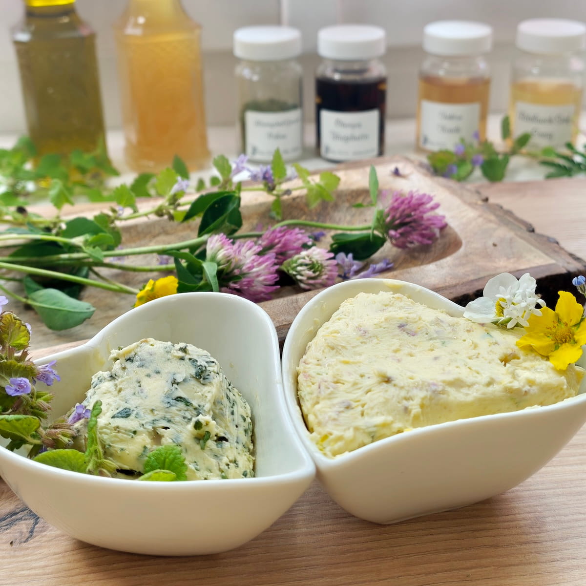 Angeschnittene Rolle Wildkräuterbutter mit grünen Kräutern und Blüten Angeschnittene Rolle Wildkräuterbutter mit grünen Kräutern und Blüten