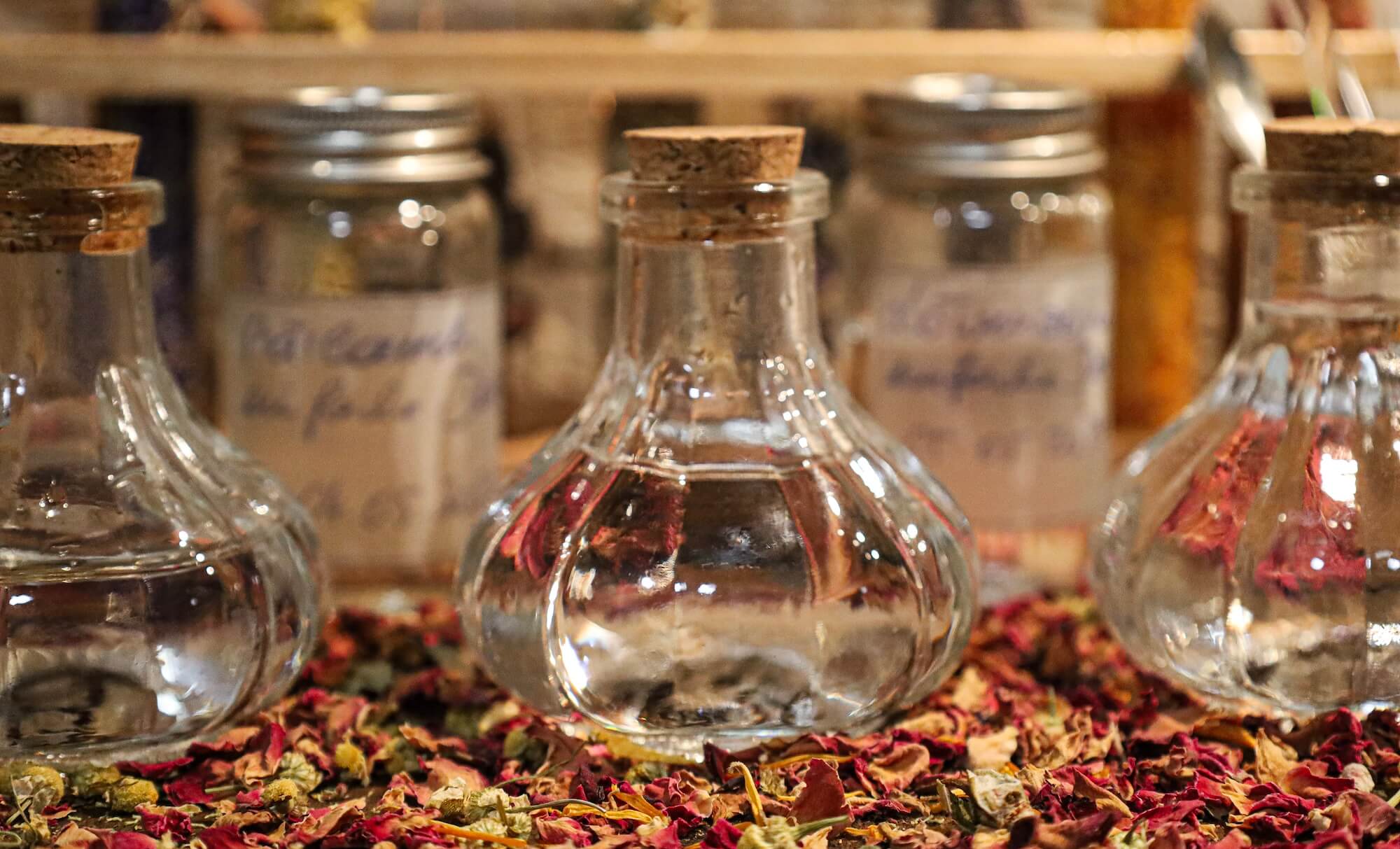 Glasflaschen mit Pflanzenwässern auf getrockneten Rosenblüten – Workshop Hydrolate und ätherische Öle Glasflaschen mit Pflanzenwässern auf getrockneten Rosenblüten – Workshop Hydrolate und ätherische Öle